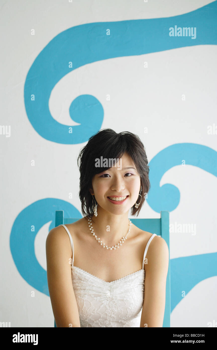 Young woman sitting on chair, looking at camera Stock Photo - Alamy