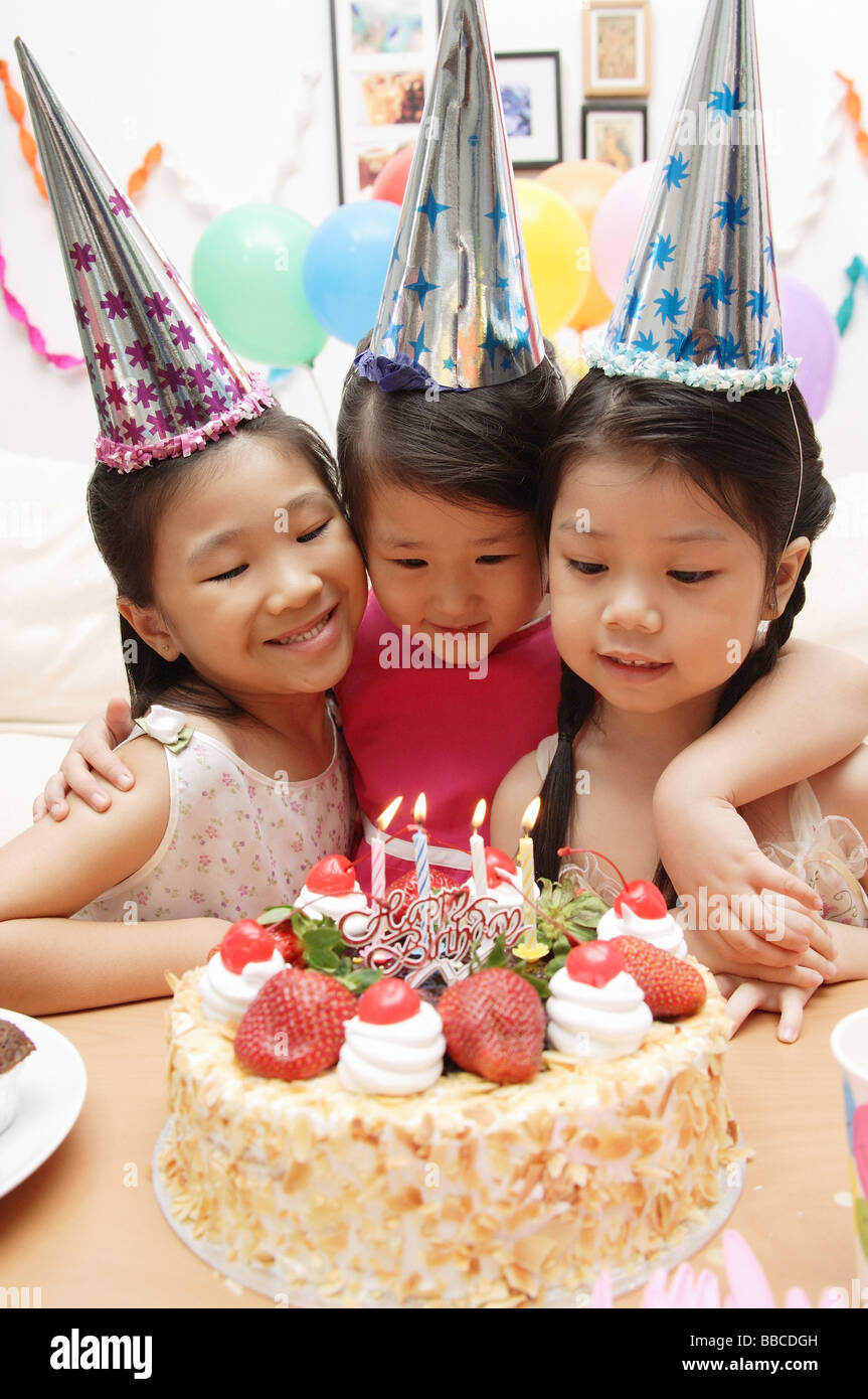 Three girls celebrating a birthday, looking at cake Stock Photo - Alamy