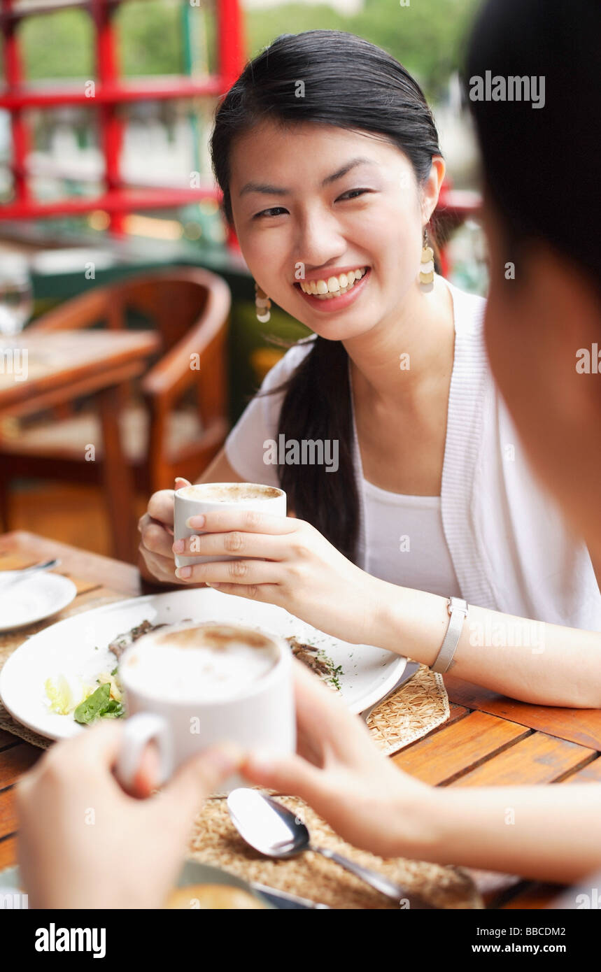 Women eating out, holding cups of coffee Stock Photo Alamy