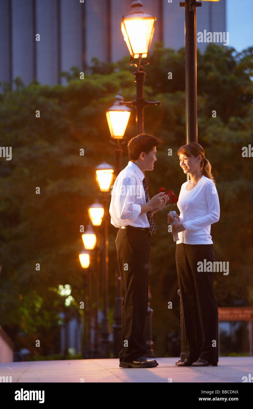 Couple standing face to face, under streetlights Stock Photo