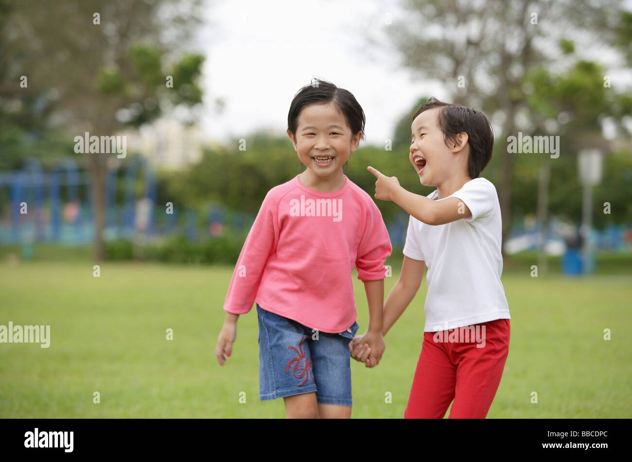 Young girls holding hands in park, laughing Stock Photo - Alamy