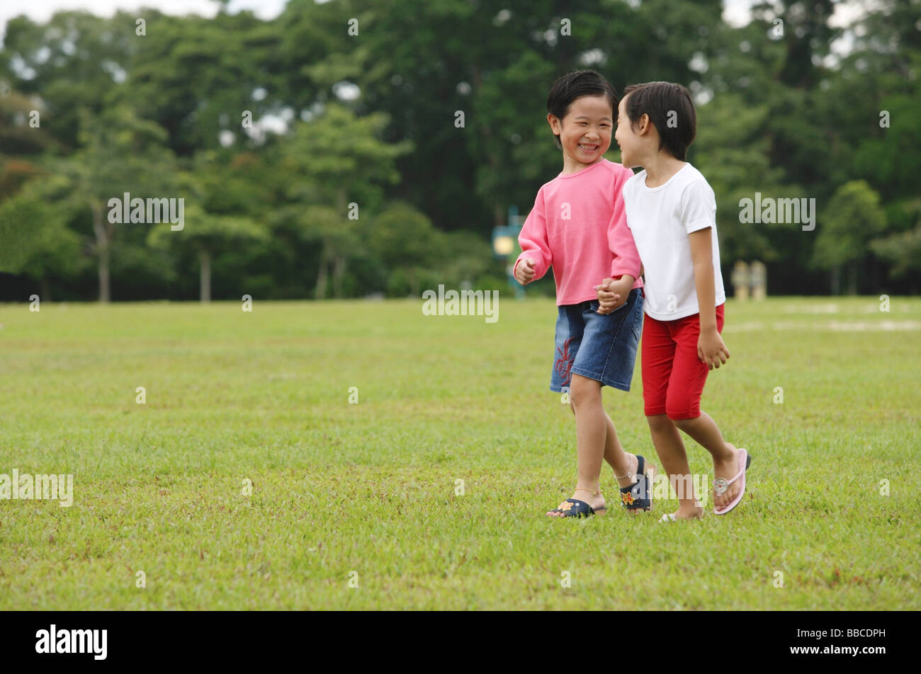 Two girls walking in park, holding hands Stock Photo - Alamy