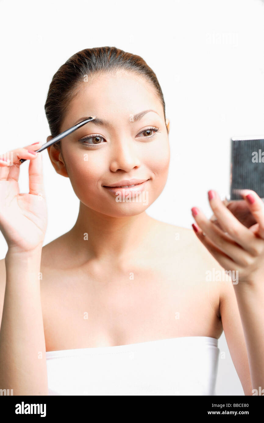Young woman using eyebrow brush, looking at compact Stock Photo - Alamy