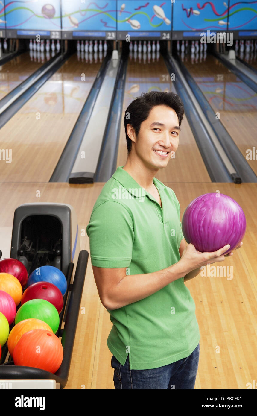 Man in bowling alley, holding bowling ball, looking at camera Stock