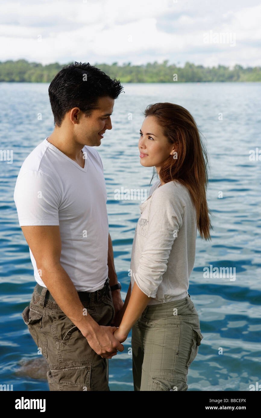 Couple standing hand in hand by lake Stock Photo