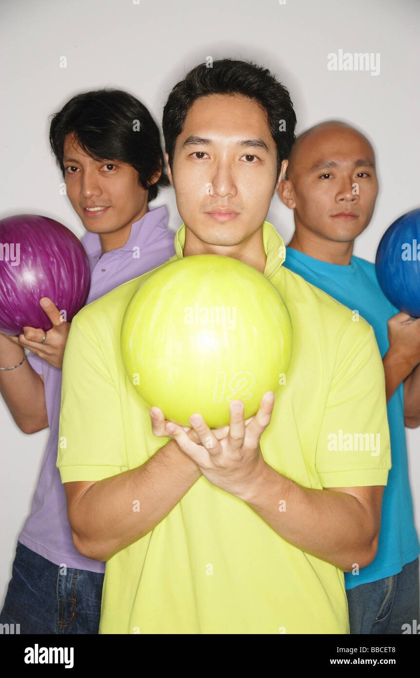 Three men standing carrying bowling balls, looking at camera Stock