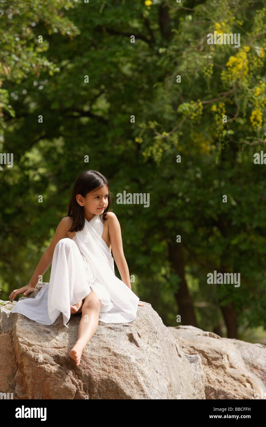 girl in white sari, sitting on rock Stock Photo