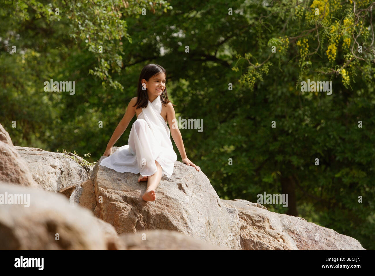 girl in white sari, sitting on rock Stock Photo