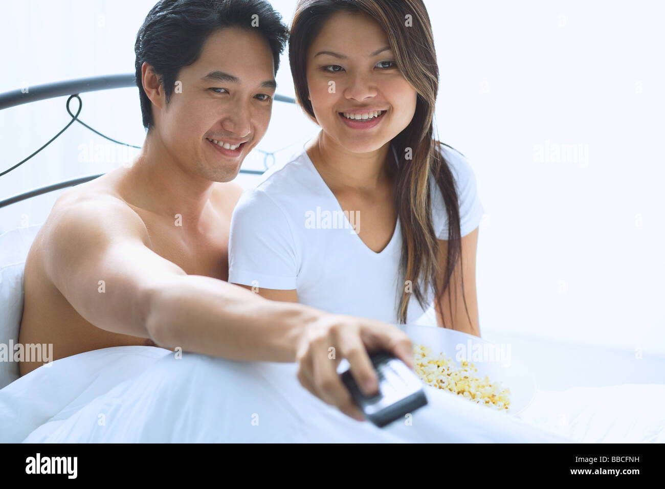 Couple sitting on bed, watching TV Stock Photo Alamy