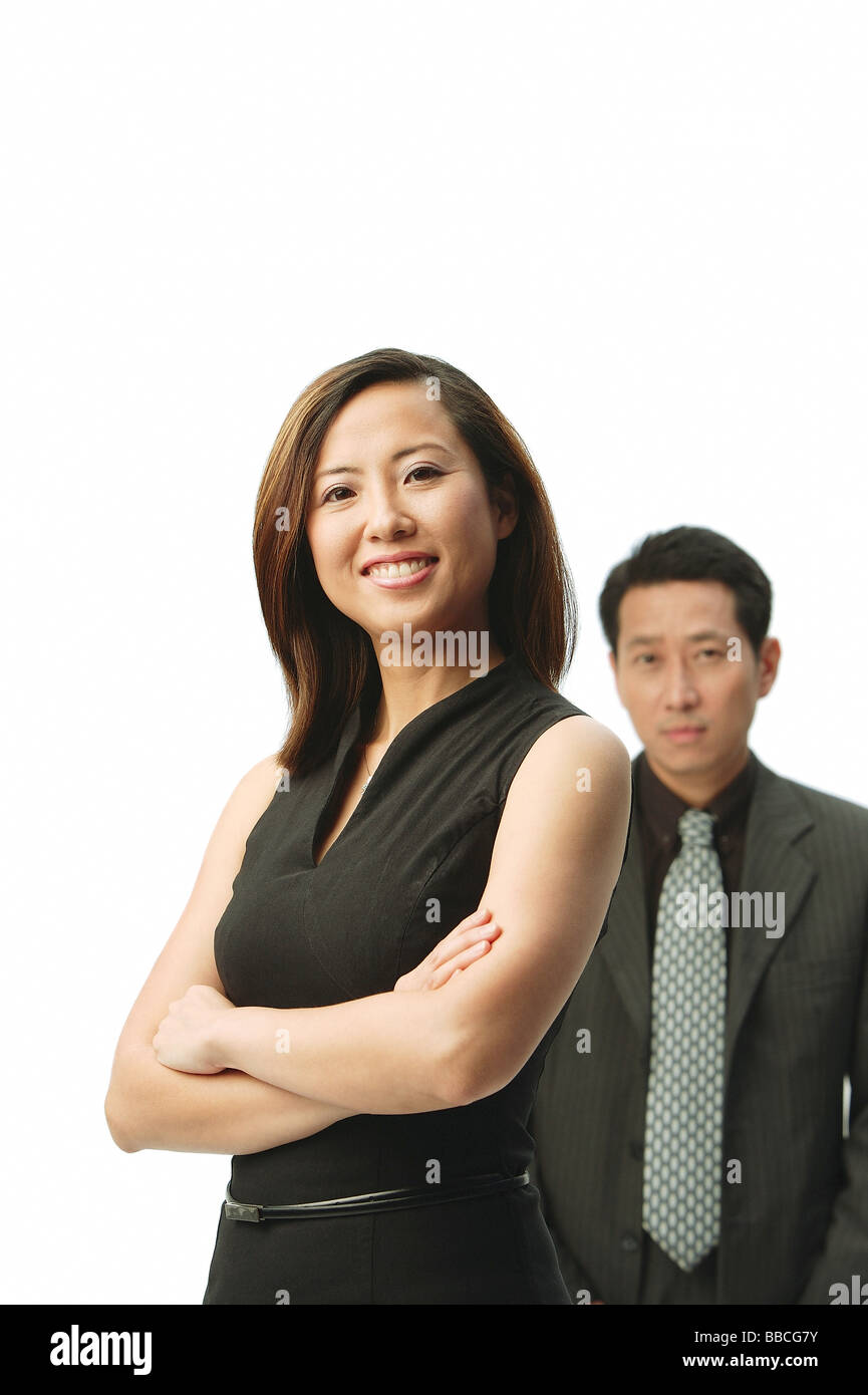 Woman with arms crossed, smiling at camera, man standing behind her