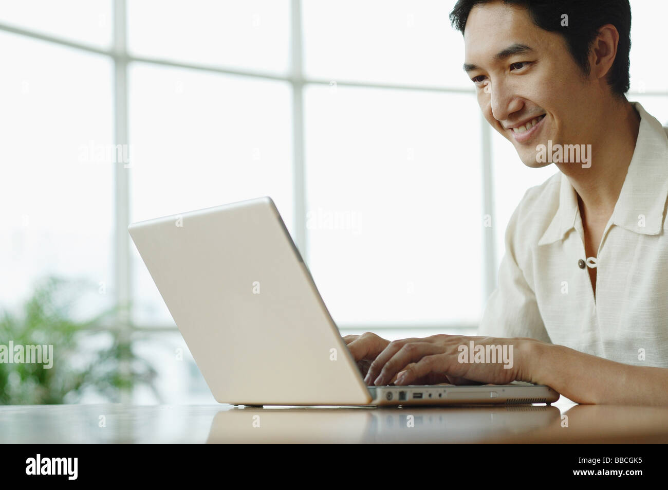 Man sitting, using laptop, smiling Stock Photo
