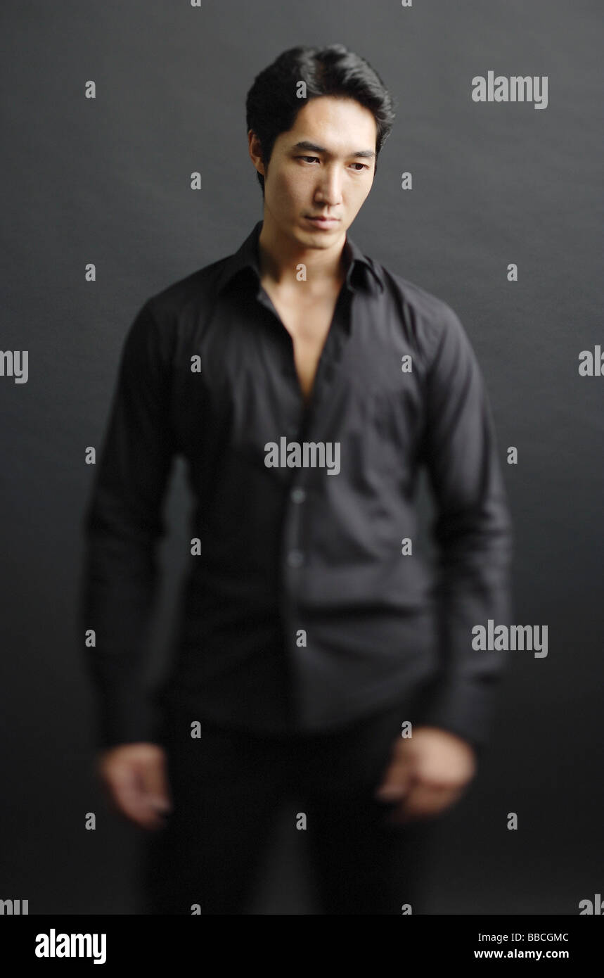 Man dressed in black, standing against black background Stock Photo - Alamy