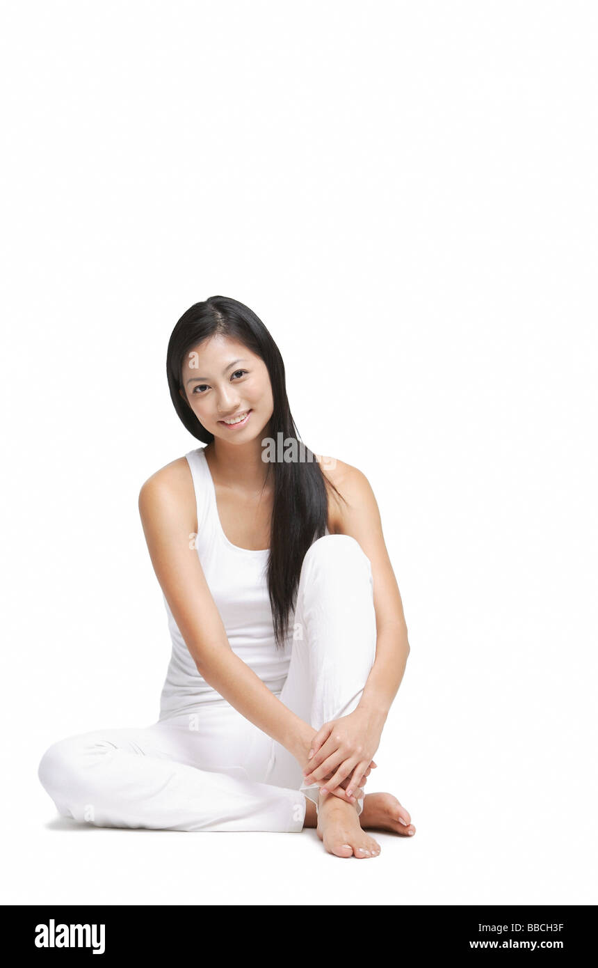 Woman sitting on floor, hugging knee, looking at camera Stock Photo - Alamy
