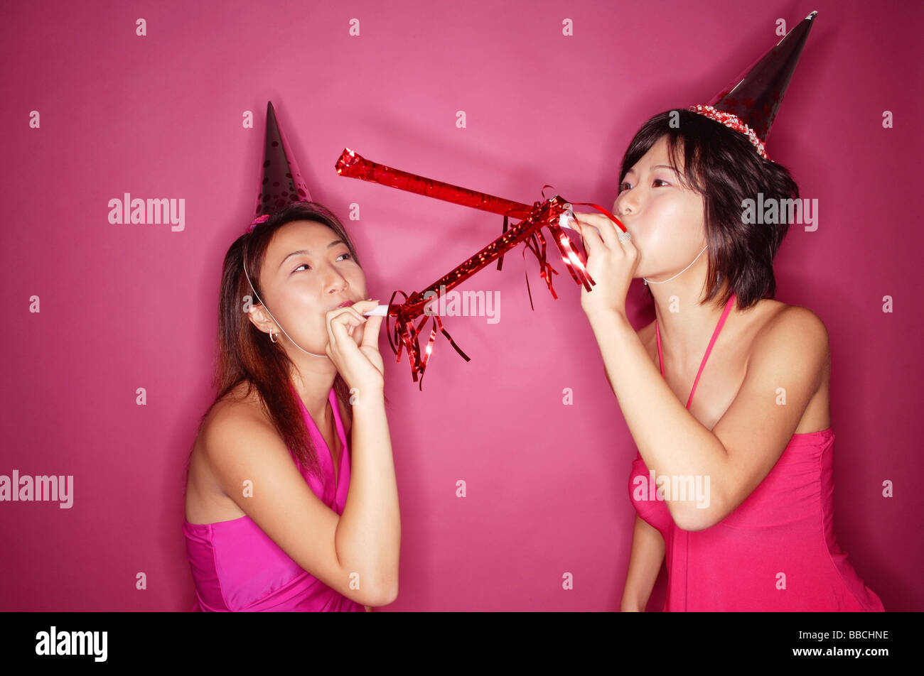 Young women wearing party hats, blowing noisemakers Stock Photo Alamy