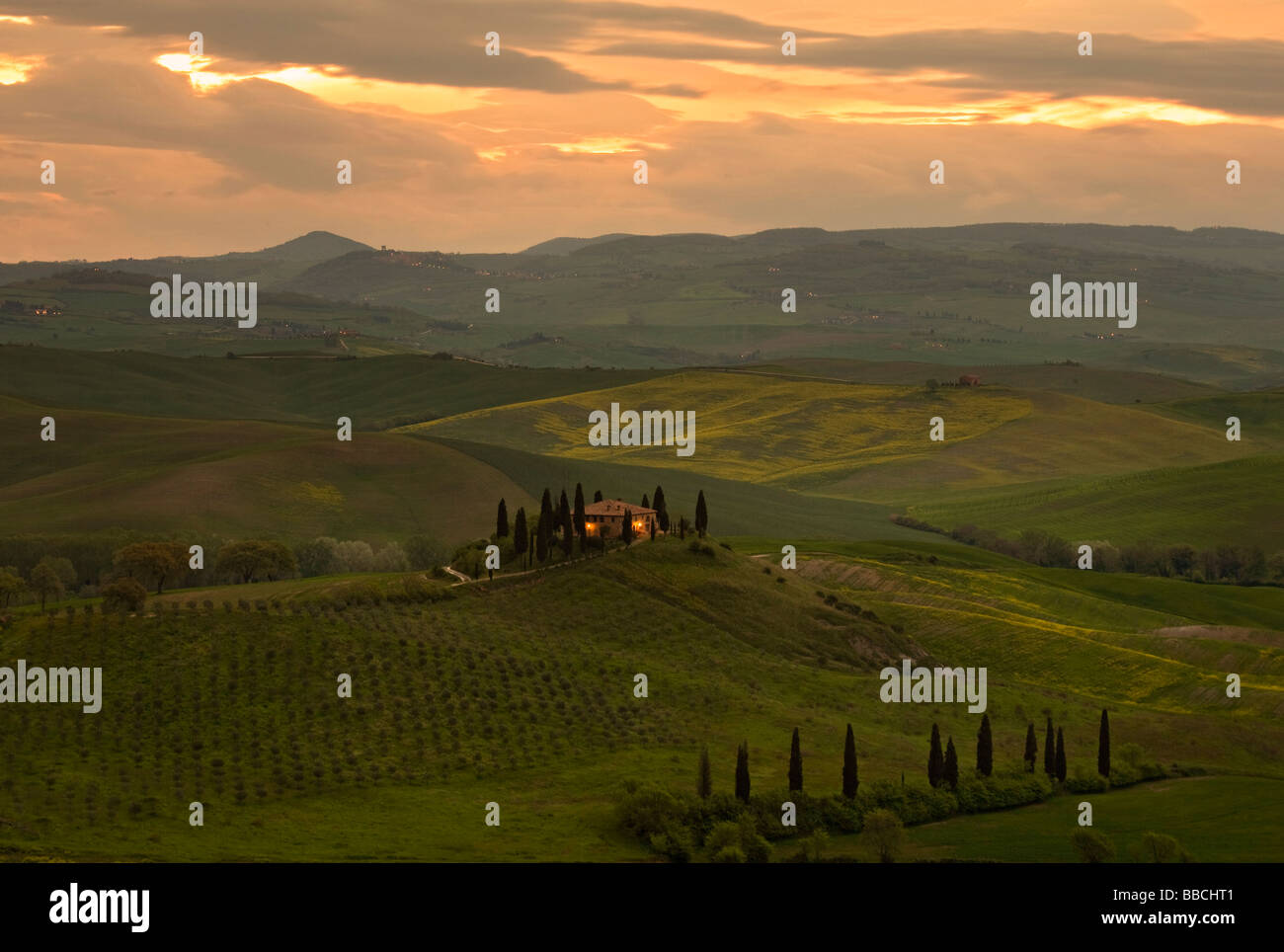 Typical Tuscan villa in early morning light with sun rising over the rolling hills of Val D'orcia, Tuscany, Italy. Stock Photo