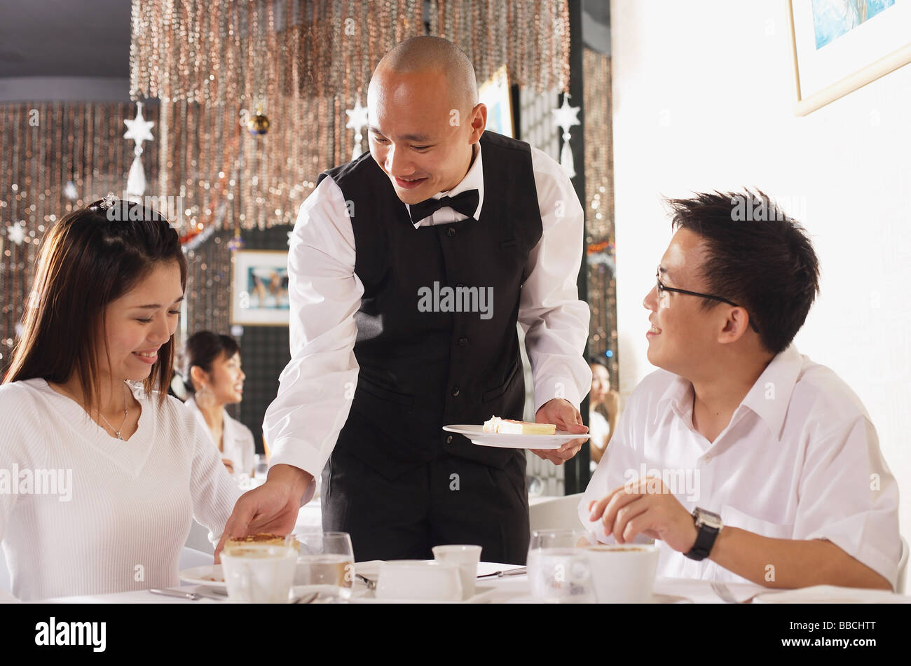 Couple in restaurant, waiter serving plates of dessert Stock Photo Alamy