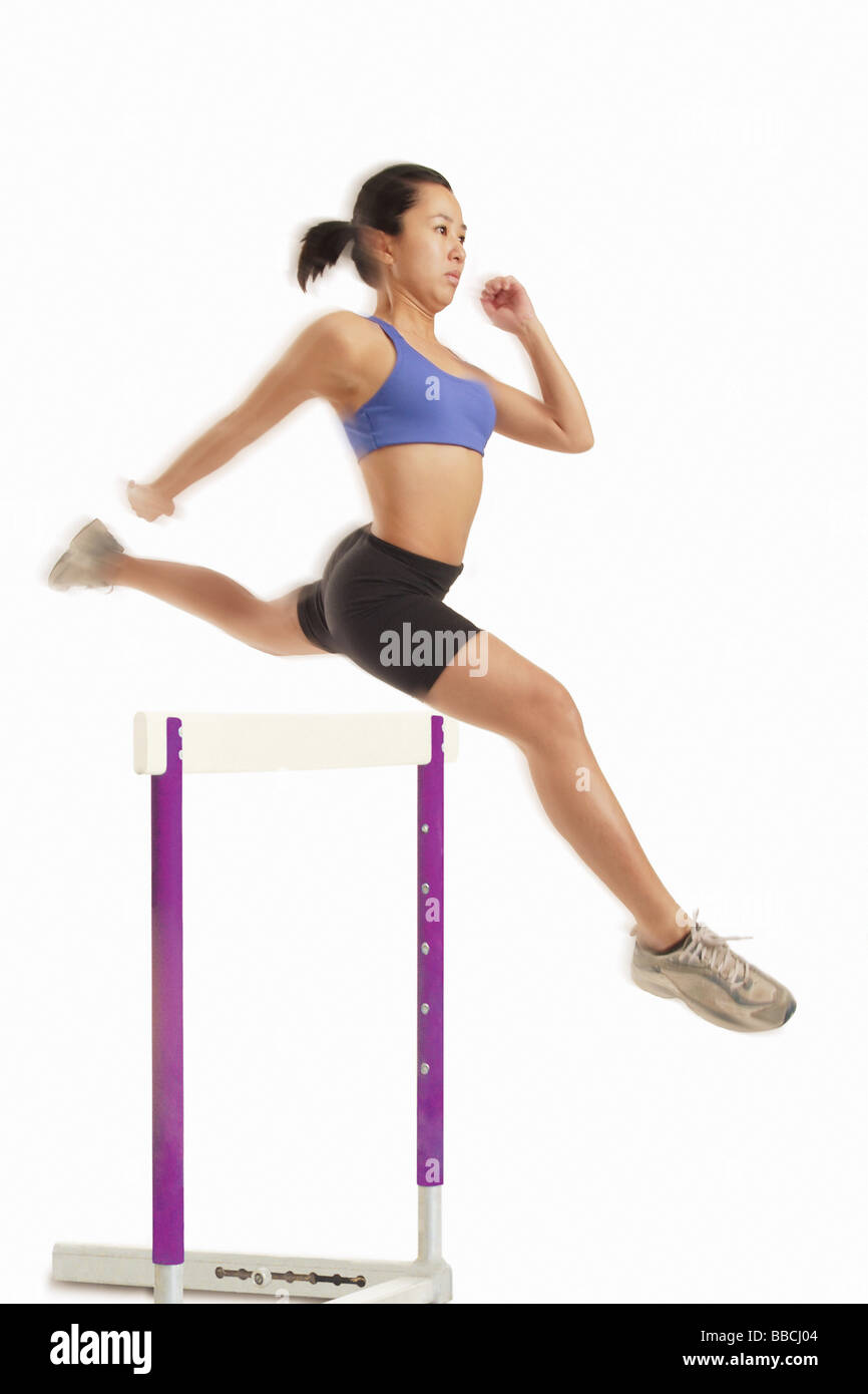 Woman jumping over hurdle Stock Photo - Alamy