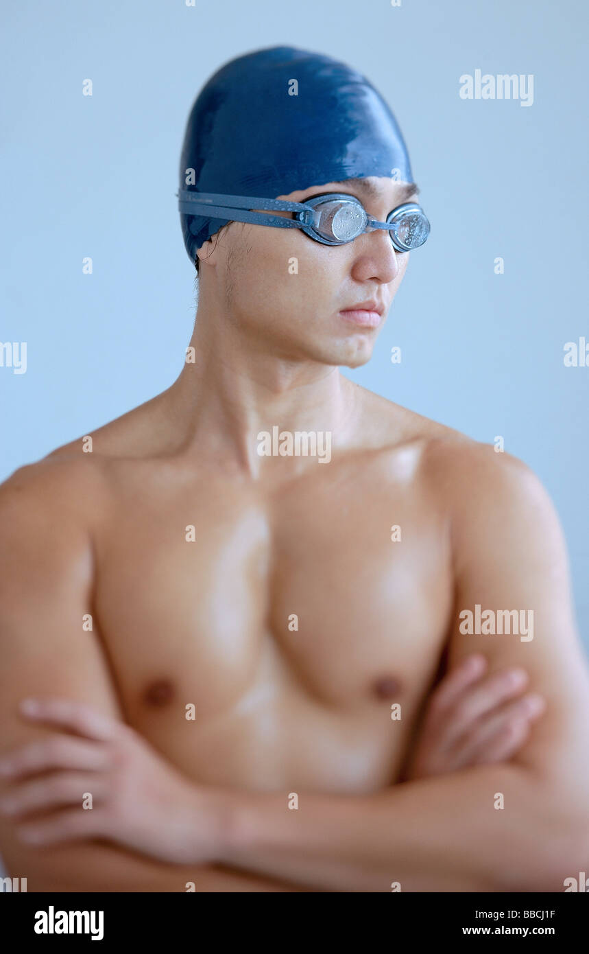 Man wearing swimming cap and goggles, arms crossed Stock Photo