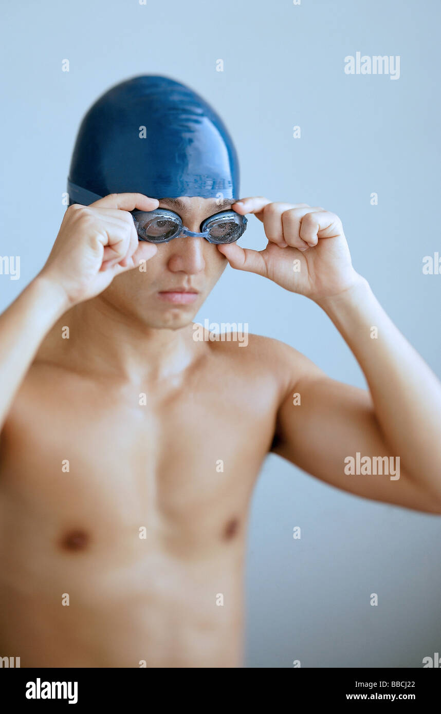 Man adjusting goggles, wearing swimming cap Stock Photo