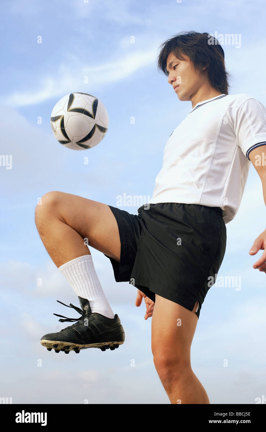 Man bouncing soccer ball on knee Stock Photo Alamy