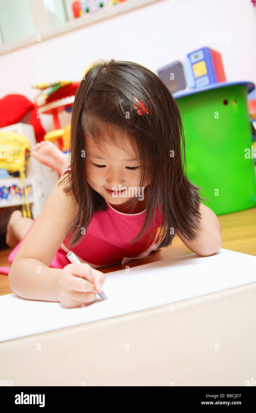 Young girl lying on floor drawing Stock Photo - Alamy