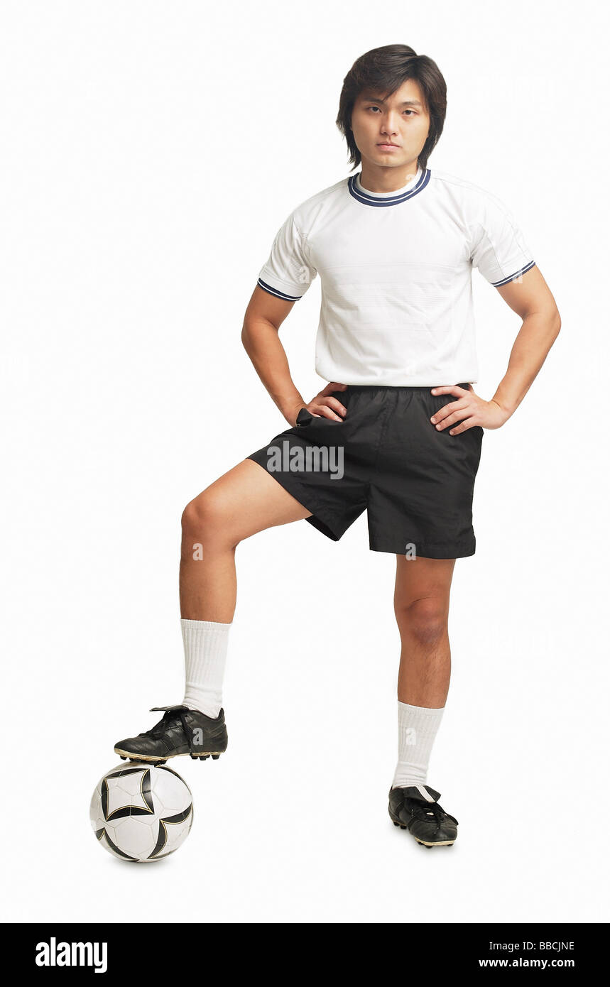 Man with hands on hips, one leg on soccer ball Stock Photo