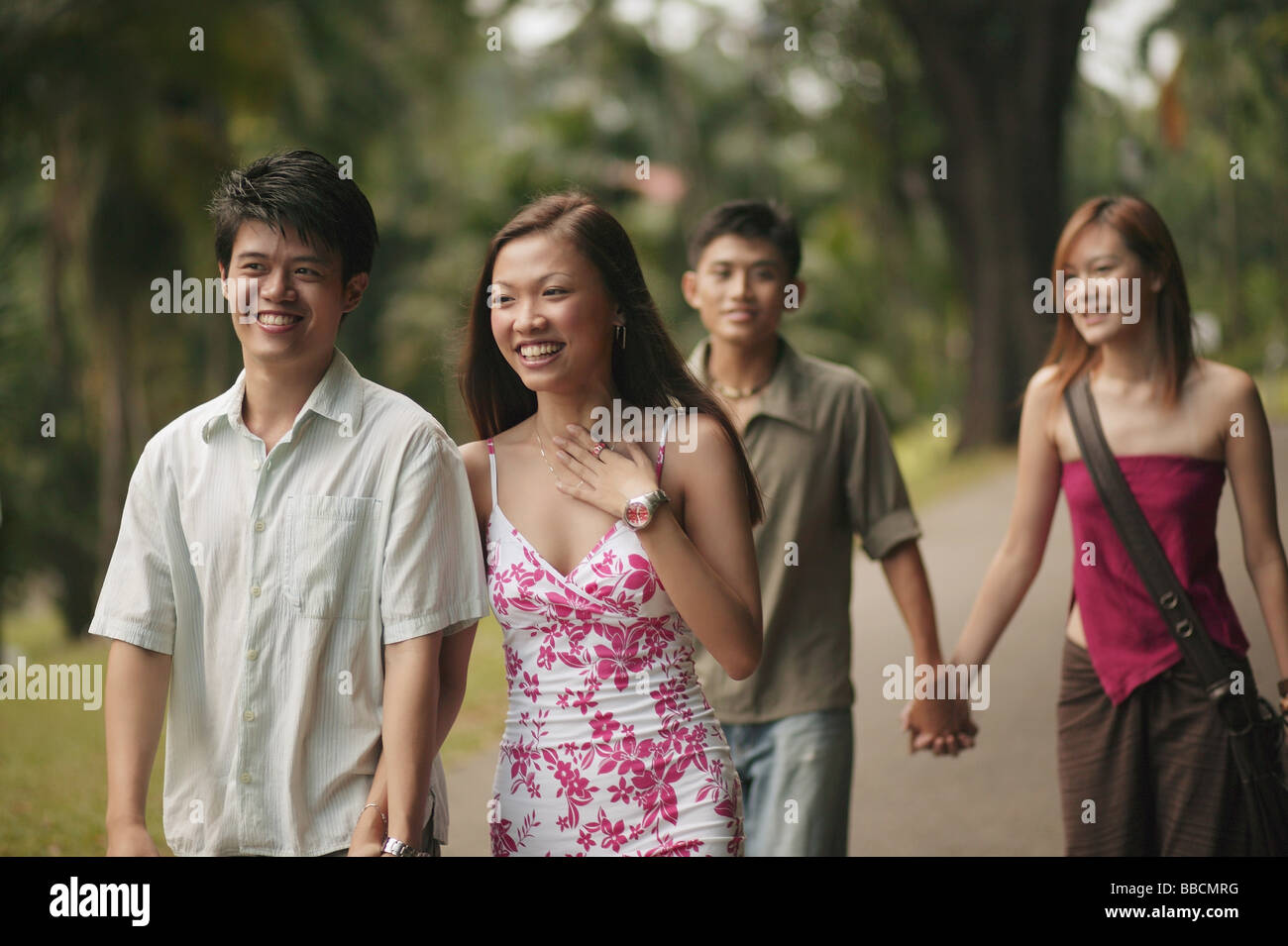 Couples walking hand in hand in park Stock Photo - Alamy