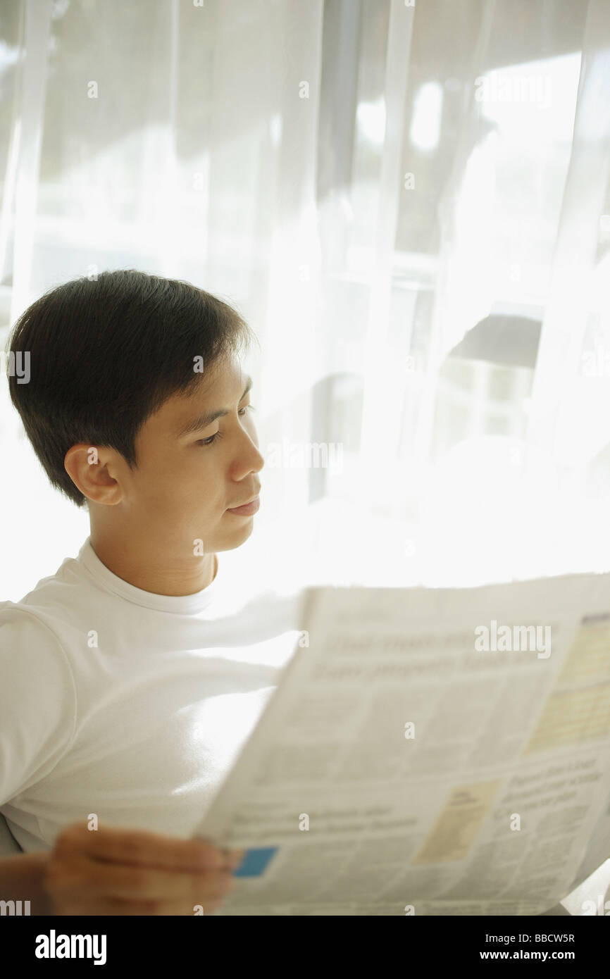 Young man reading newspaper Stock Photo - Alamy