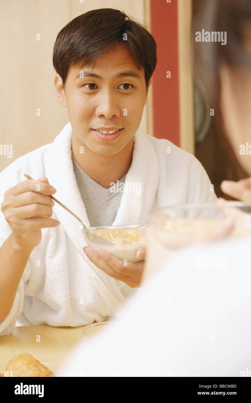 Couple sitting across each other eating cereal. Stock Photo