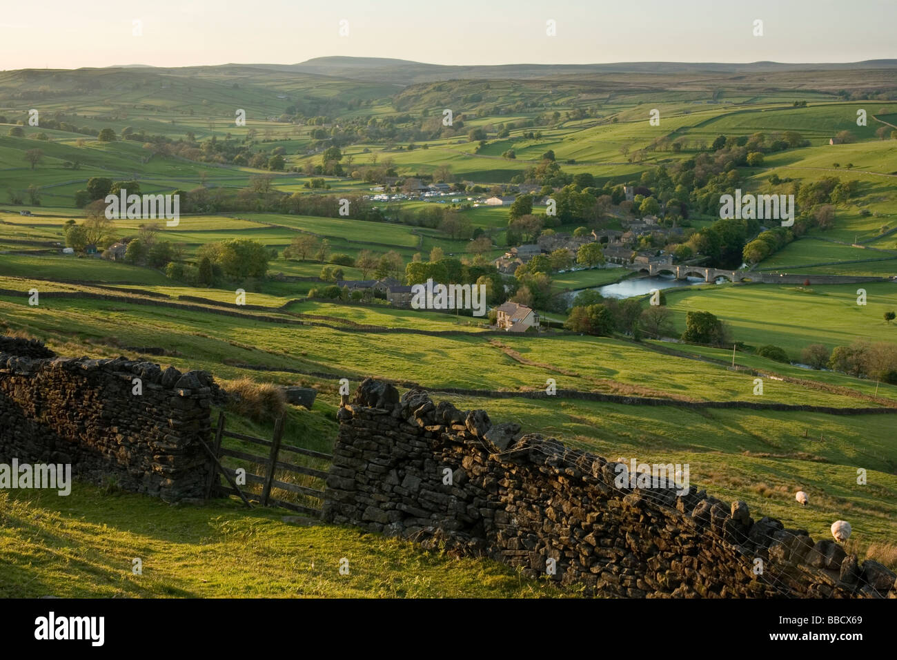 A drystone wall frames the view towards the village of Burnsall, in Wharfedale, Yorkshire Dales, from Burnsall Fell Stock Photo
