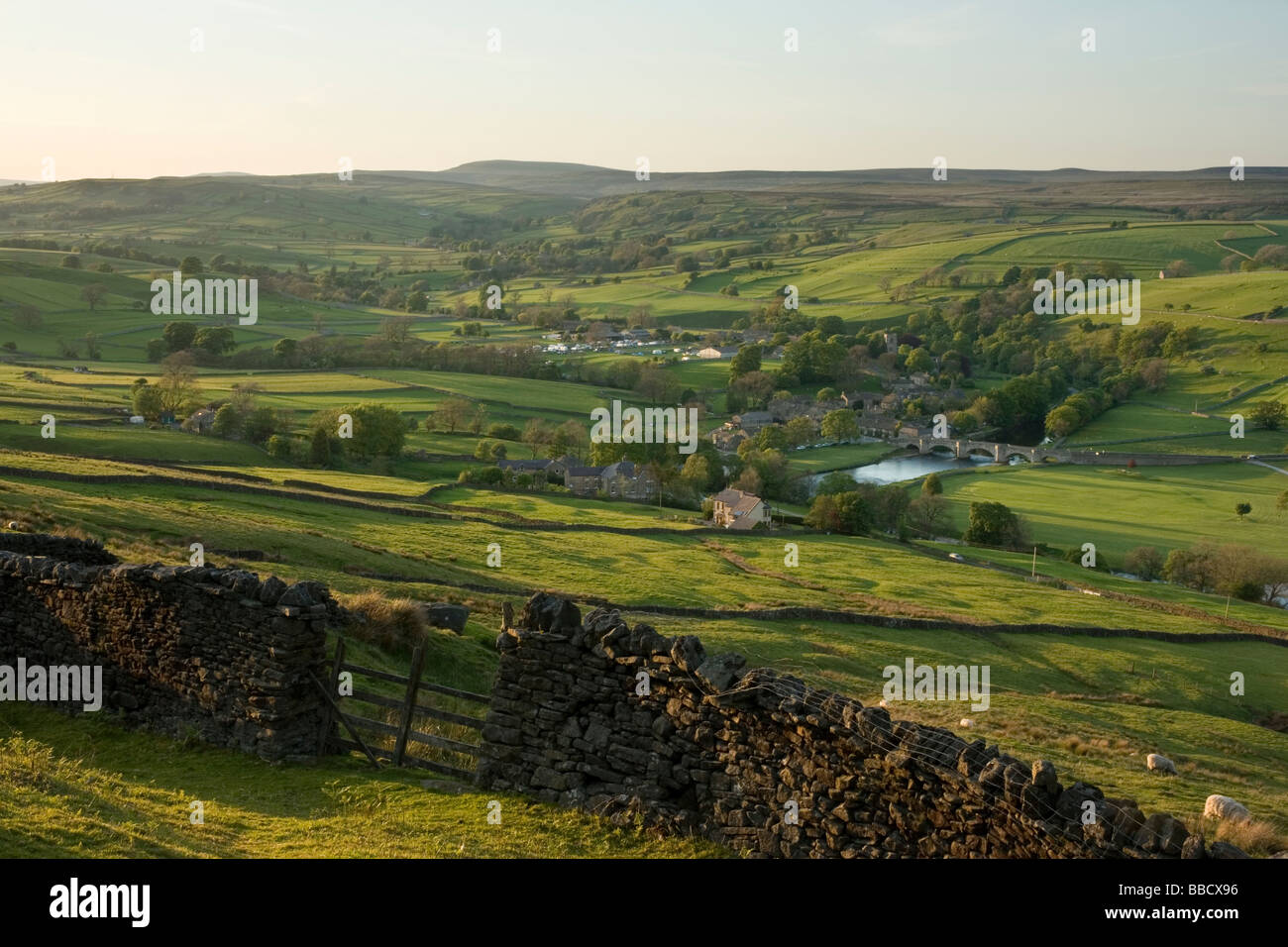 A drystone wall frames the view towards the village of Burnsall, in Wharfedale, Yorkshire Dales, from Burnsall Fell Stock Photo