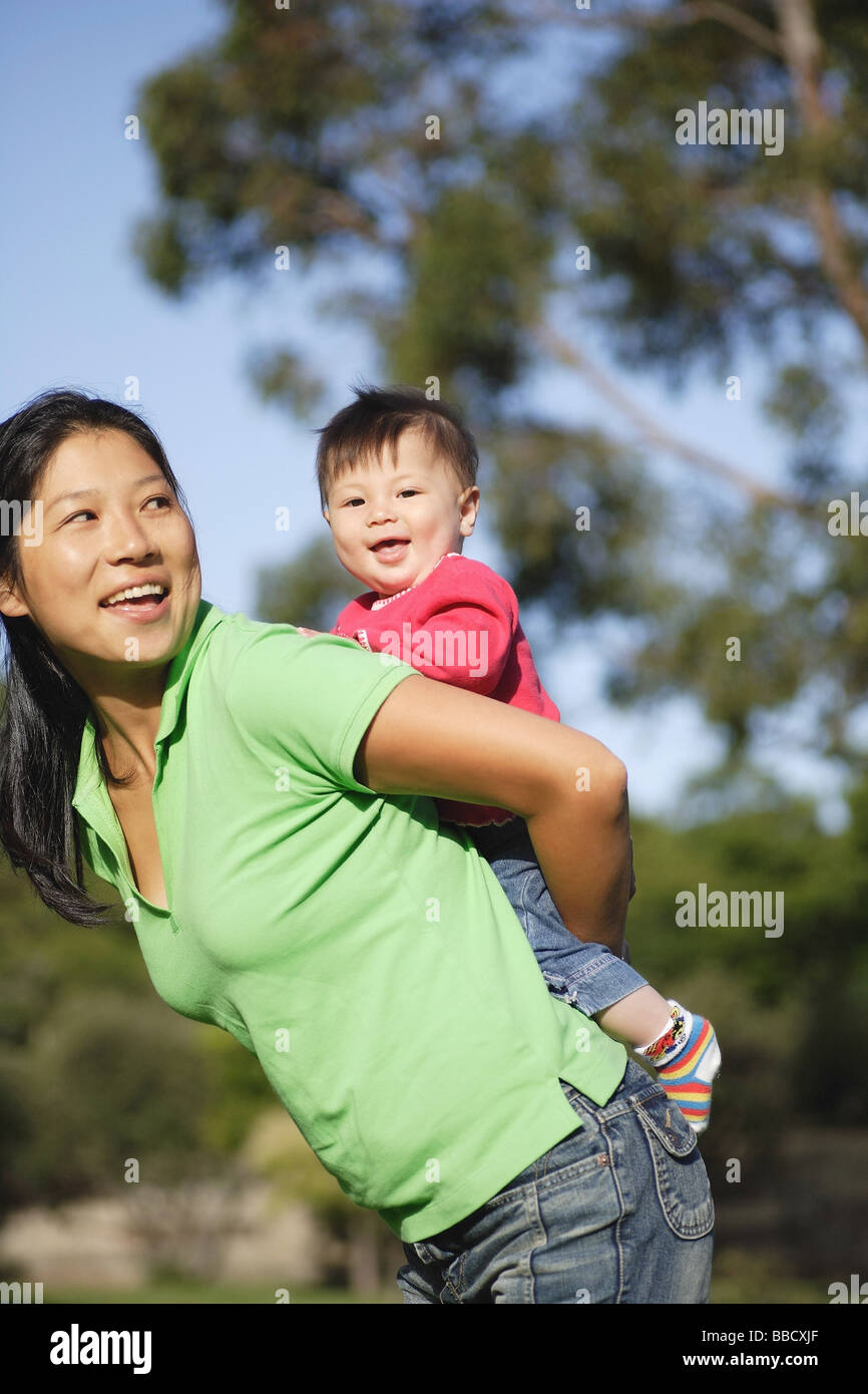 Mother carrying baby girl on her back, sideview Stock Photo Alamy