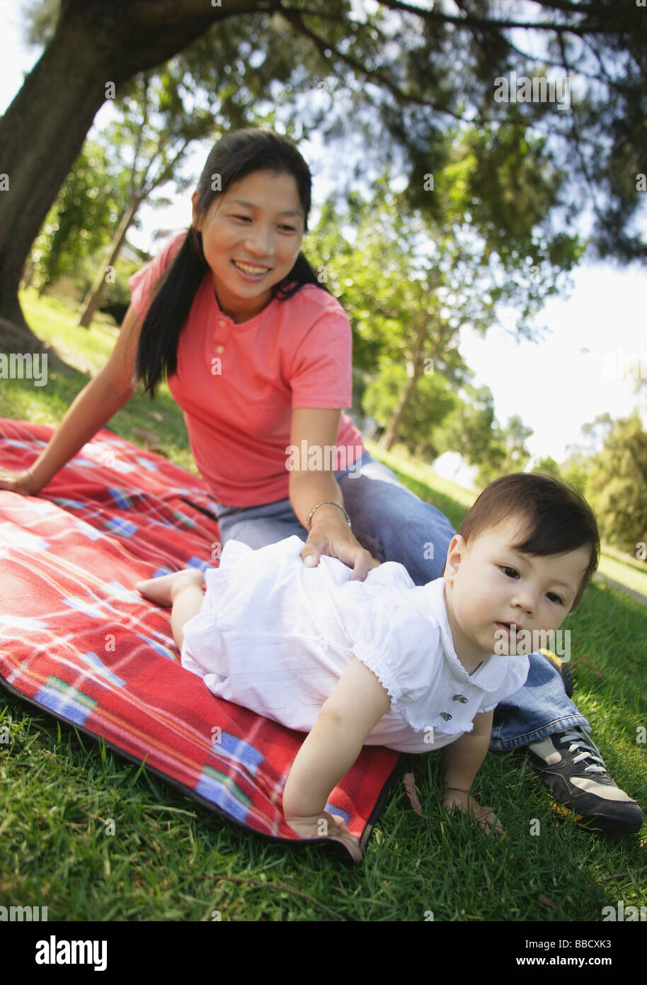 Mother and daughter on picnic blanket in park Stock Photo