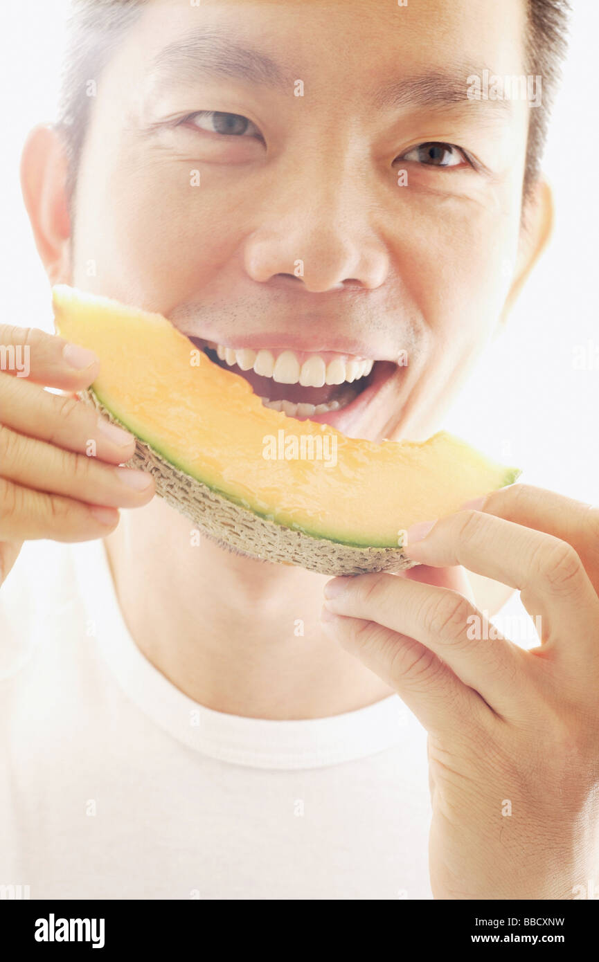 Man eating melon, smiling Stock Photo Alamy