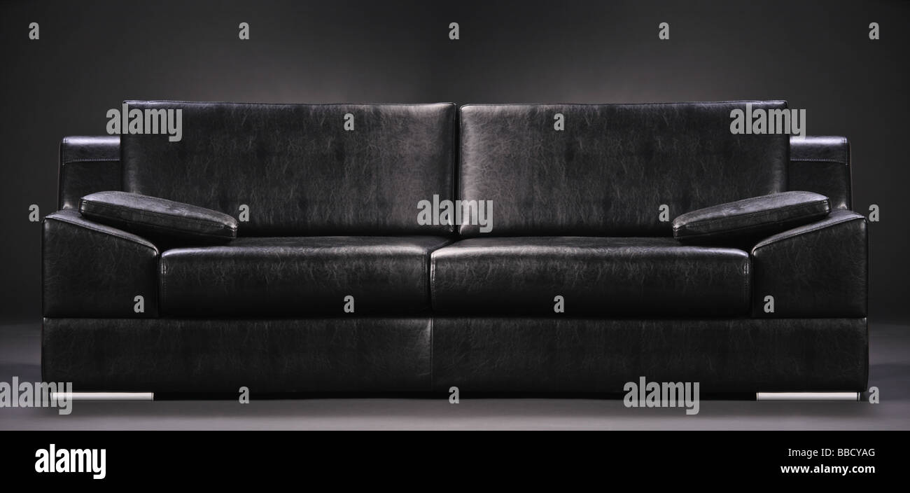 Modern black sofa isolated against black background Stock Photo - Alamy
