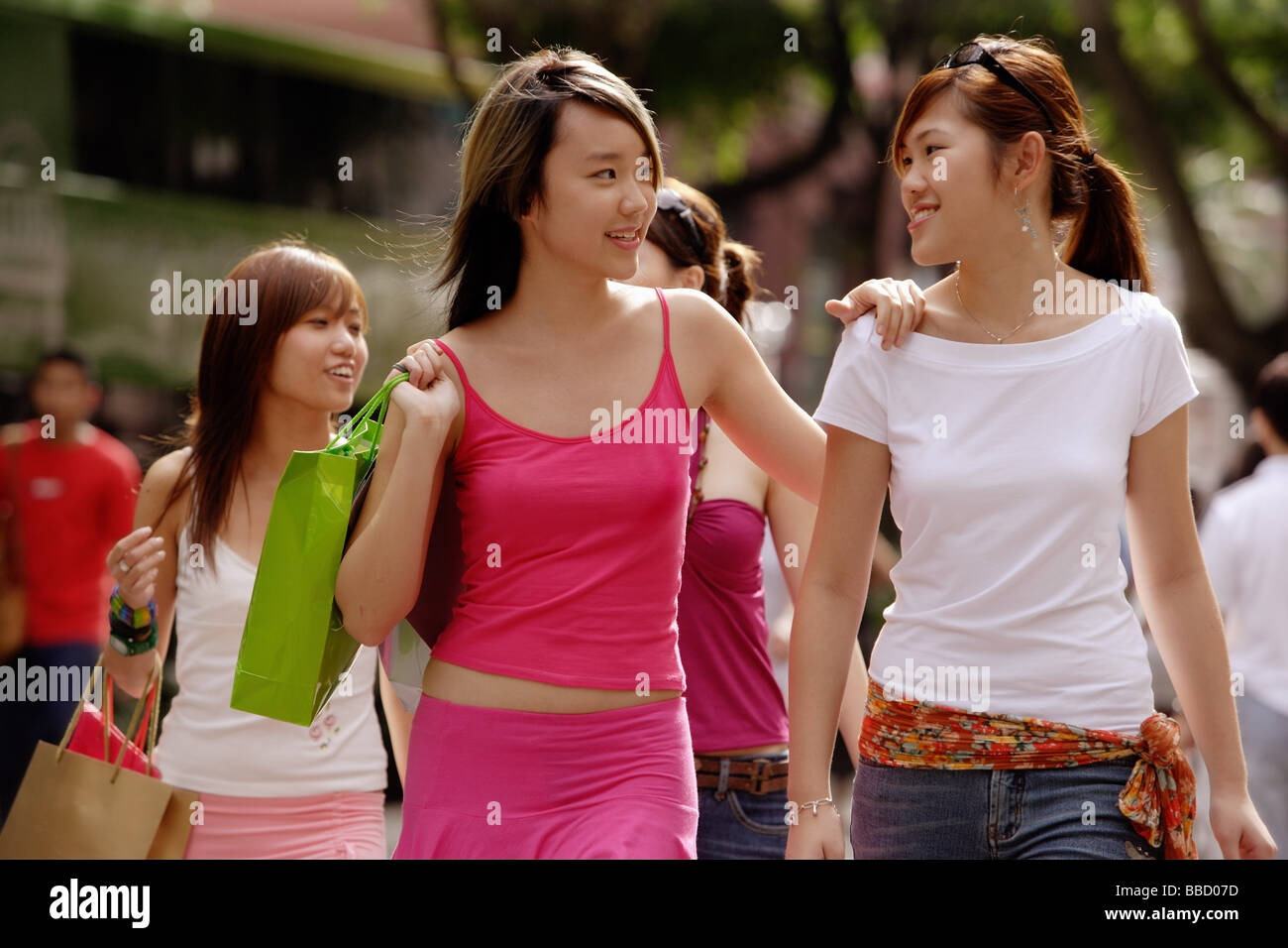 Young women walking side by side, carrying shopping bags Stock Photo ...