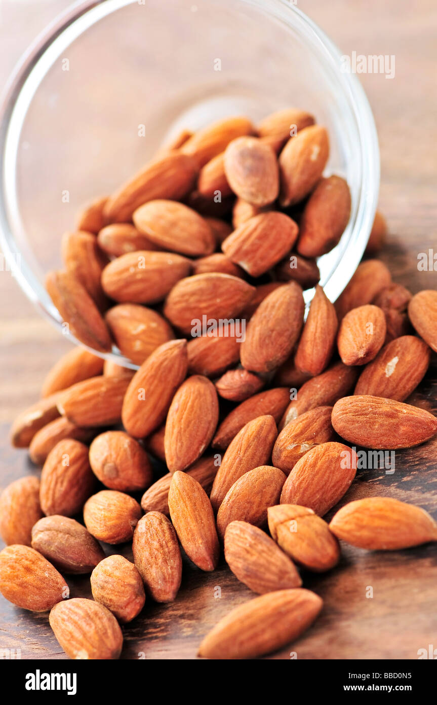 Raw almonds spilling out of small glass bowl Stock Photo