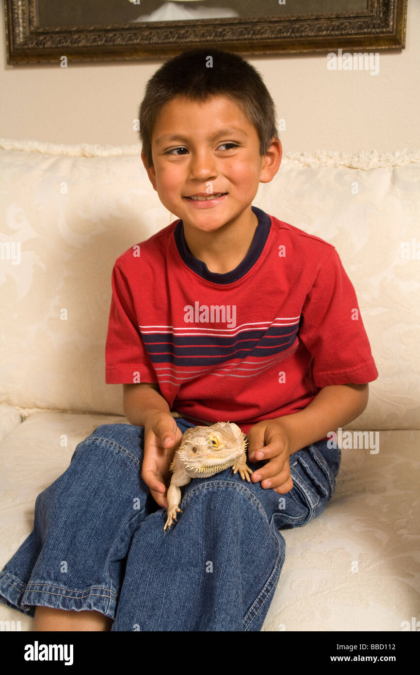 Adopted Hispanic boy 6-8 year old holds pet Bearded Dragon he adopted from animal rescue  US USA United States America POV MR  © Myrleen Pearson Stock Photo