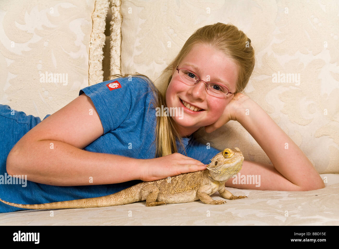 Portrait Young girl 9-11 year olds smiles at camera petting bearded dragon, copy space, cutout, caucasian,close up, closeup Stock Photo