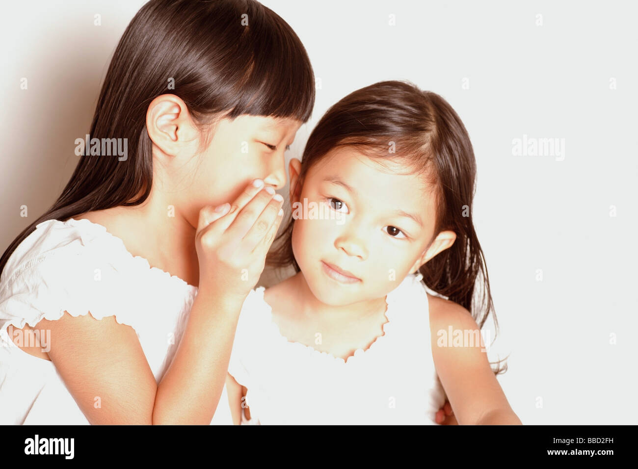 Girl whispering to another young girl Stock Photo - Alamy