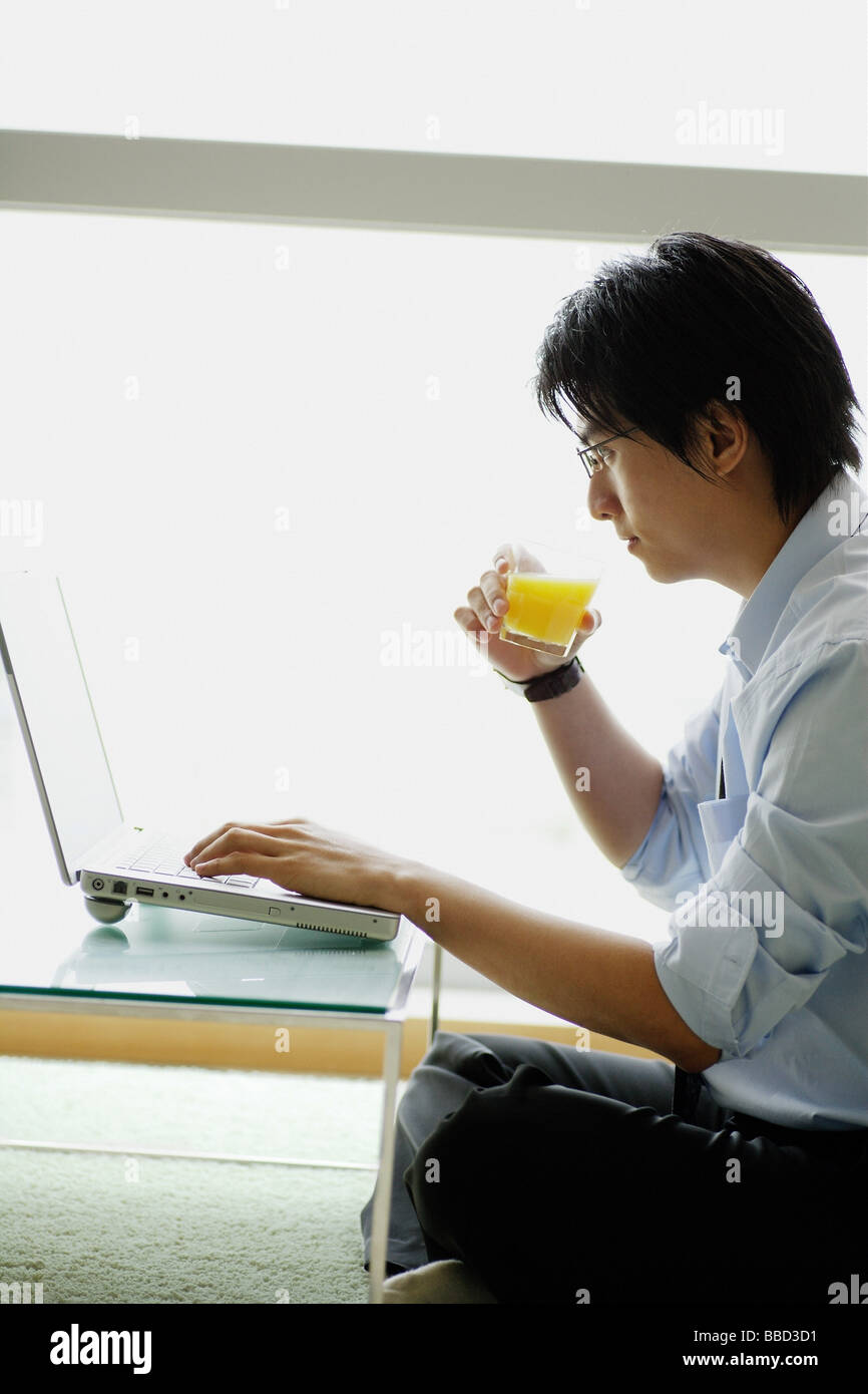 Businessman using laptop and drinking orange juice Stock Photo Alamy