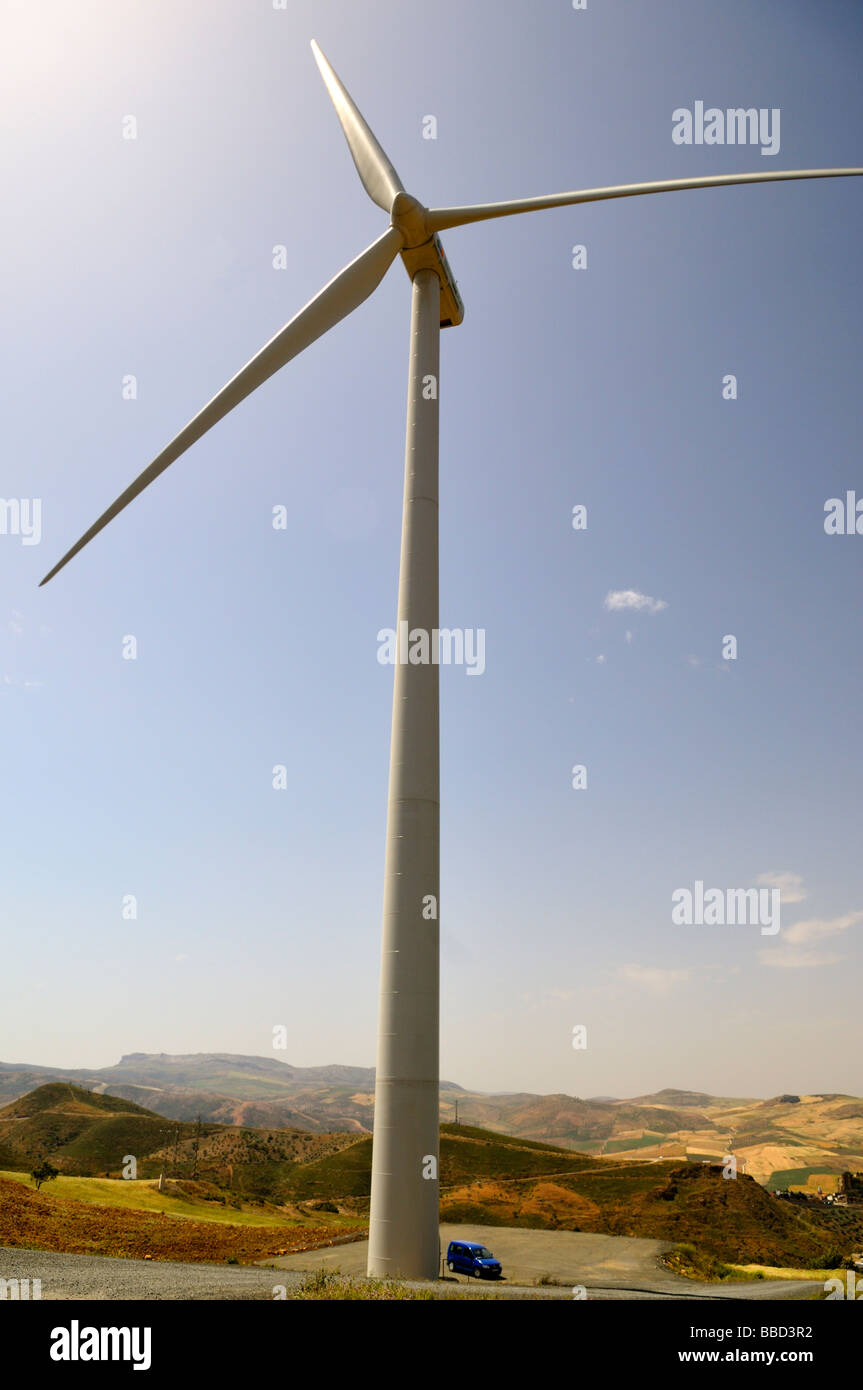 Single wind turbine tower with car parked next to base to show massive