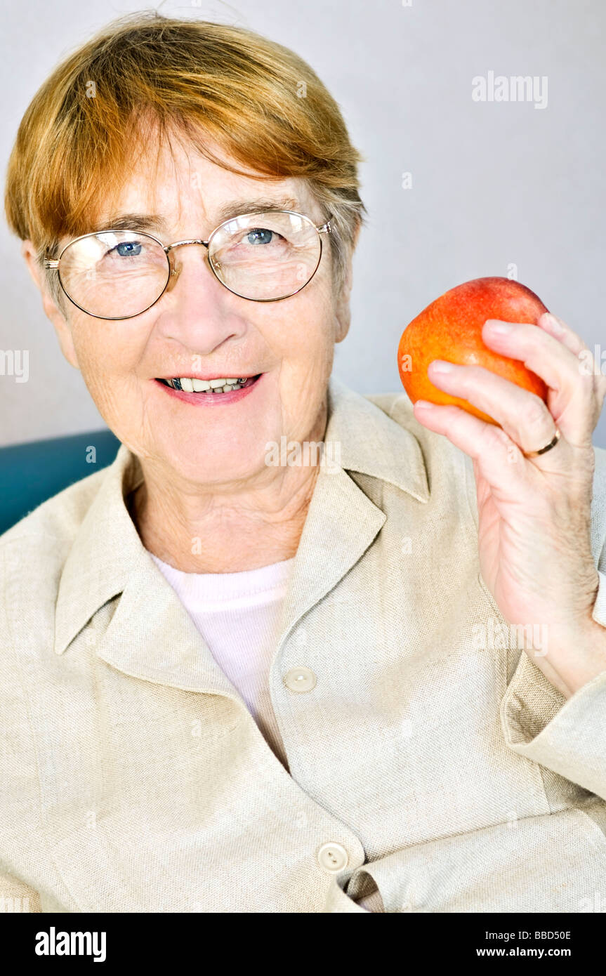 Elderly woman eating healthy holding a nutritious apple Stock Photo - Alamy