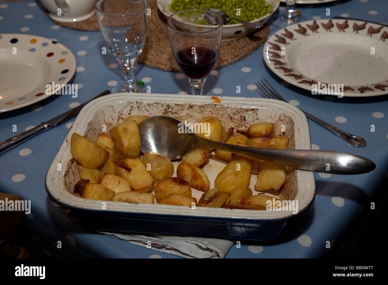 Dish of golden roast potatoes on dining table UK Stock Photo