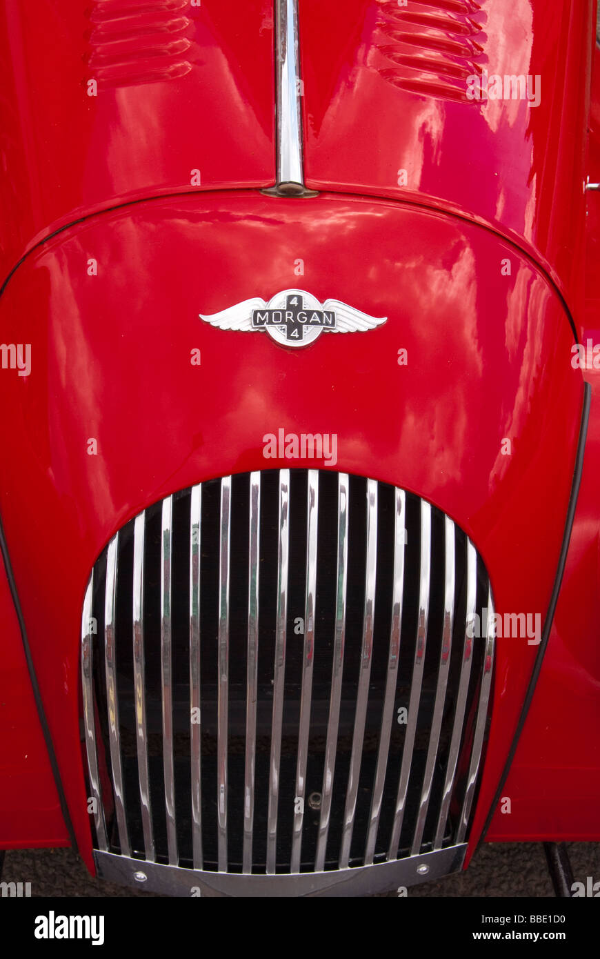 A close up of the bonnett and grill of a classic Morgan 4 sports vintage car showing the badge logo of the red vehicle Stock Photo