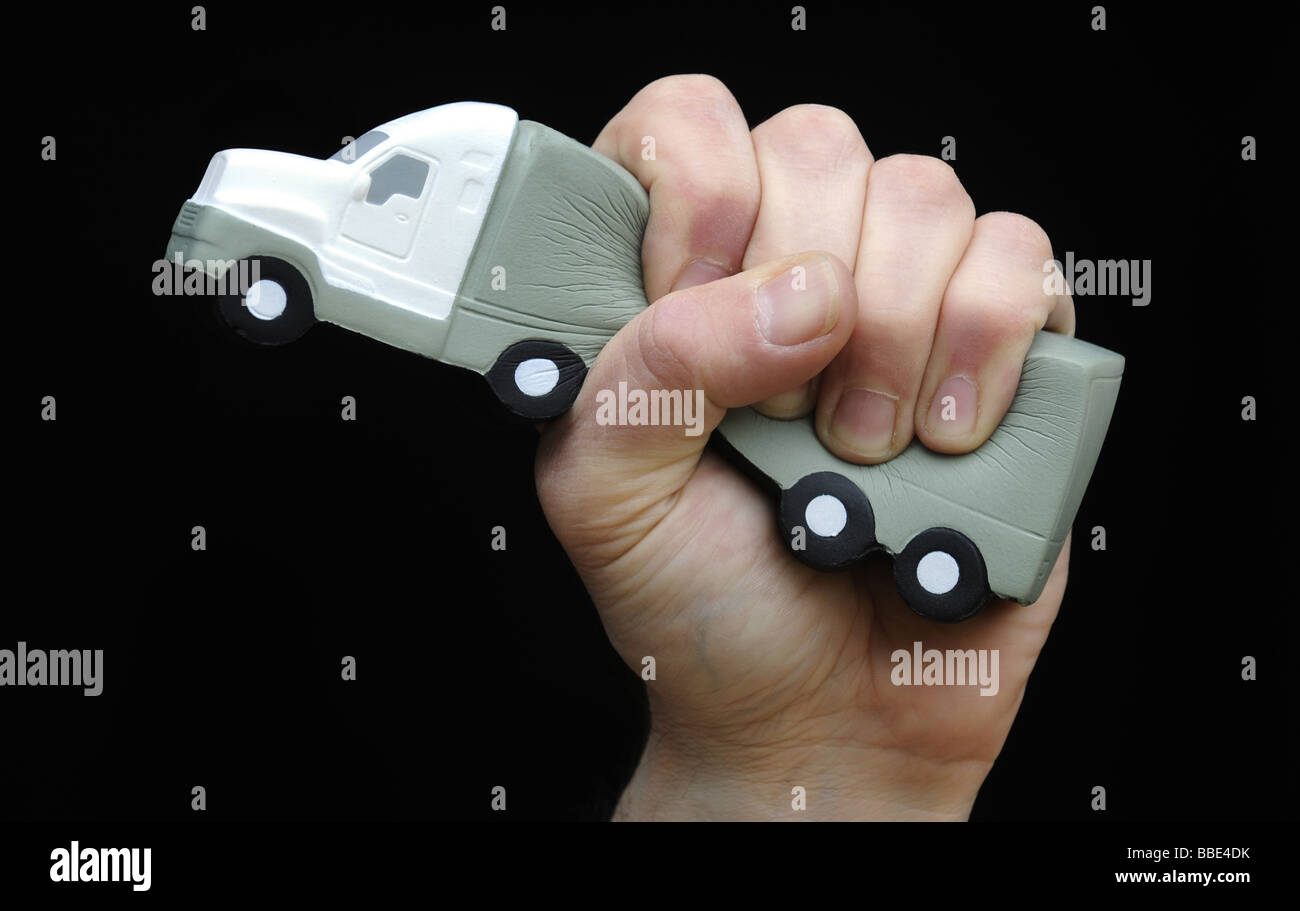 A LORRY SQUEEZED IN A  MANS HAND ILLUSTRATING RECESSION AND ECONOMIC SITUATION OF THE HAULAGE INDUSTRY,UK. Stock Photo