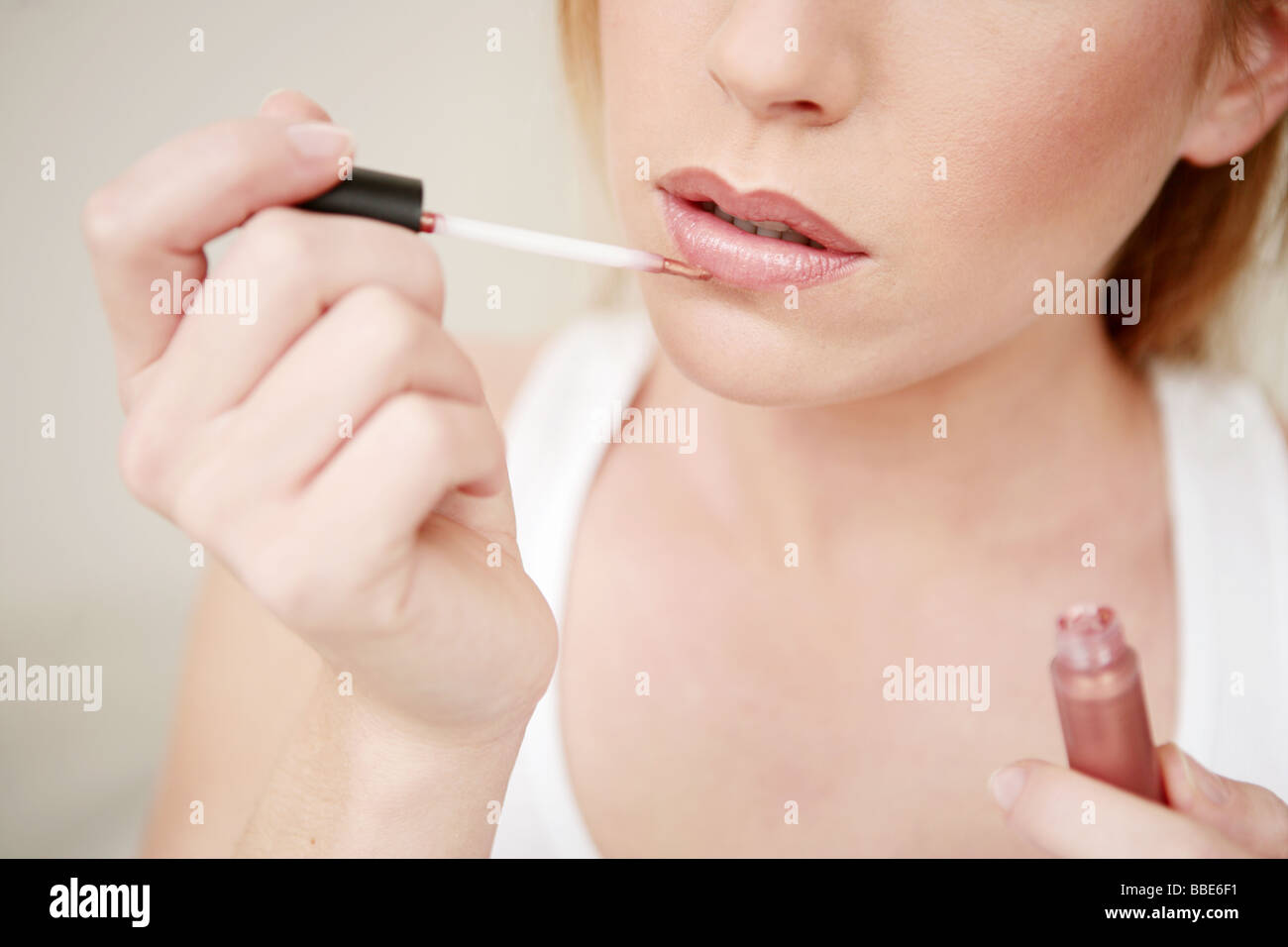 Cut out of young beauty woman's face applying lip gloss on lips Stock Photo