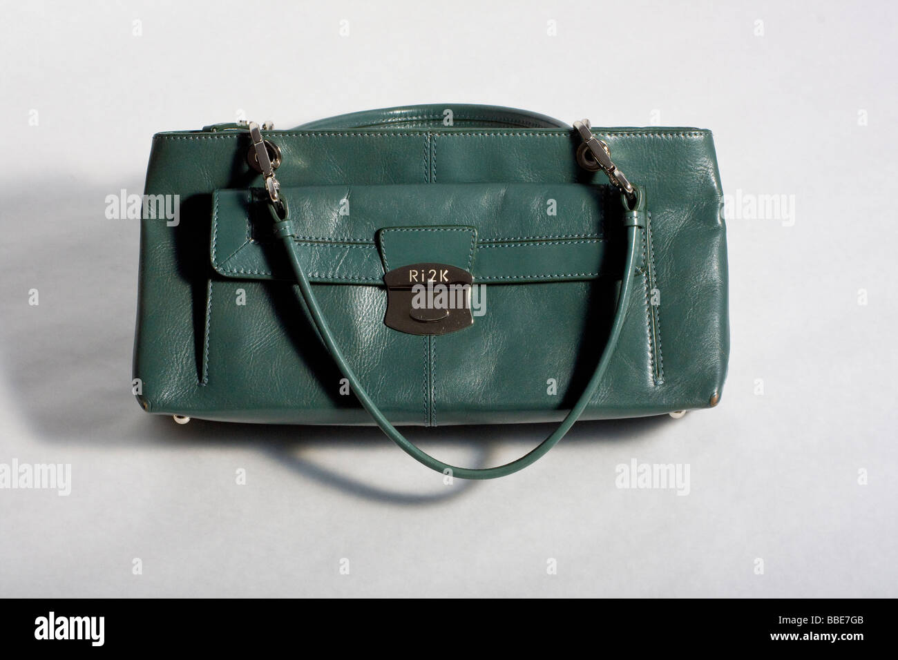 Studio shot of stylish green handbag, with metal buckle. Stock Photo
