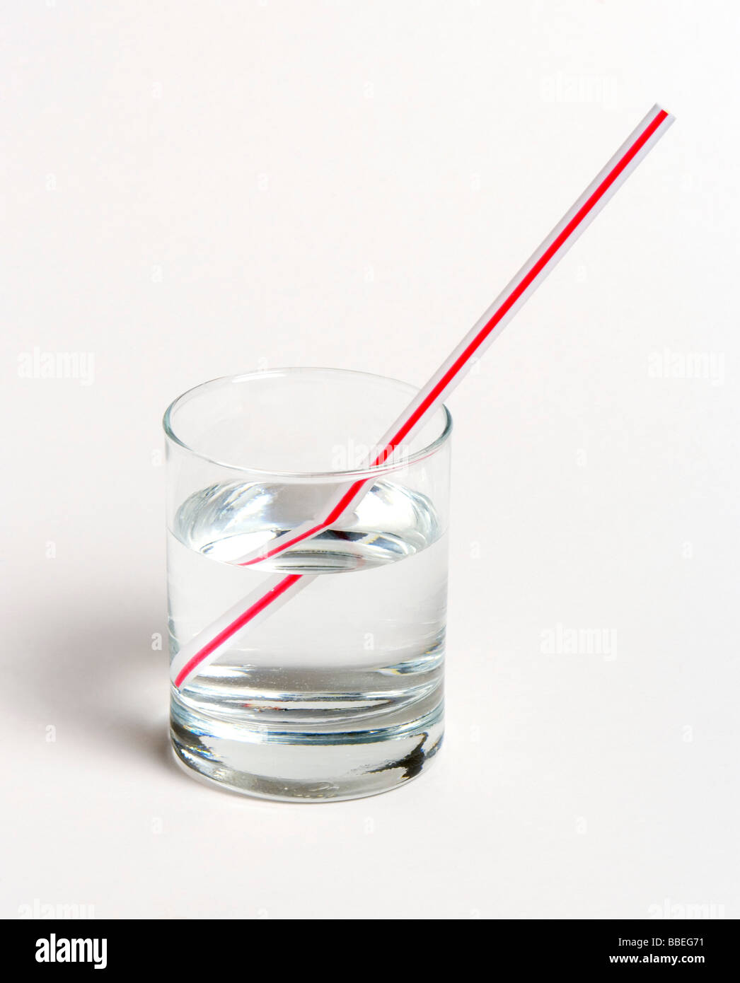 SCIENCE Optics Refraction Straw in glass of water on white background. Straw appears to be broken, due to refraction of light Stock Photo