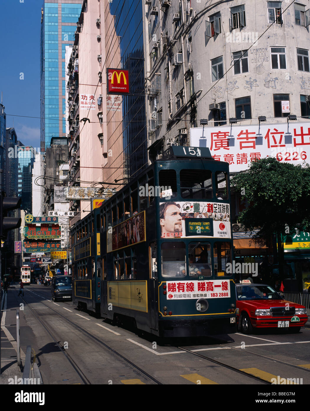 CHINA Hong Kong Island tram on busy city street with high rise buildings and advertising hoardings. Sign for McDonalds above Stock Photo